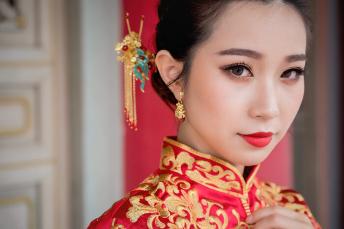 Asian bridal makeup in Toronto featuring a bride in traditional Chinese dress with red lipstick